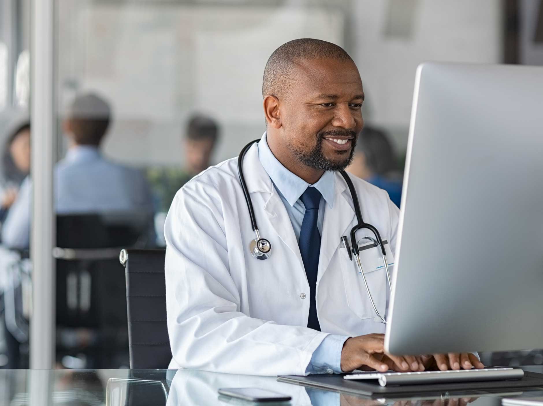 A doctor sitting at a desk, using a computer