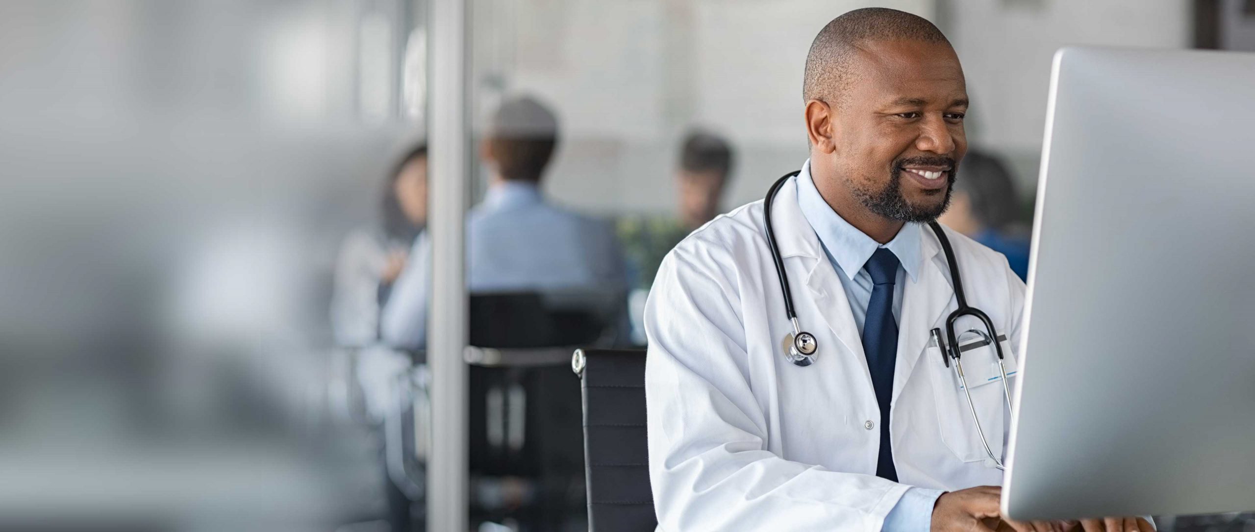 A doctor sitting at a desk, using a computer