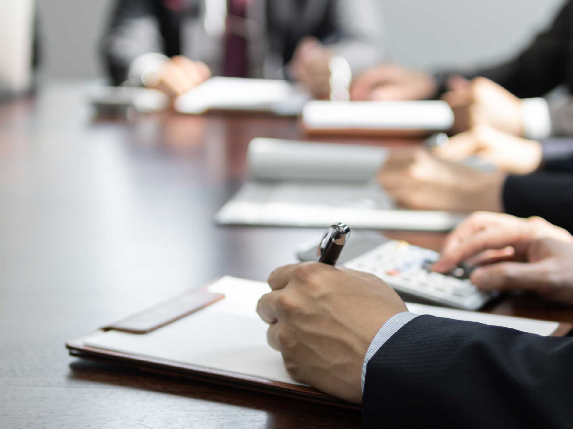 Someone writing on a clipboard, during a meeting