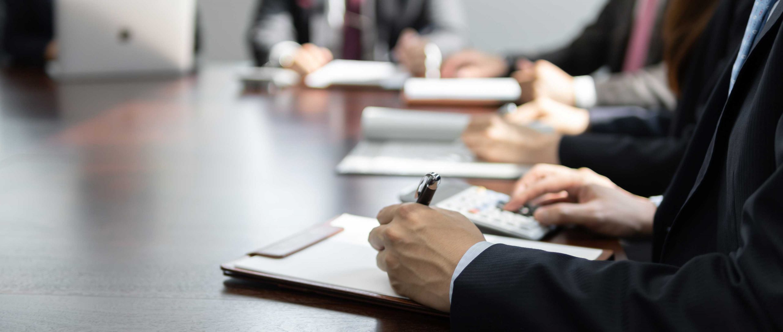 Someone writing on a clipboard, during a meeting